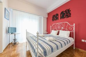 a bedroom with a white bed and a red wall at Athens Centre Flat 2 min. from Evangelismos Metro in Athens
