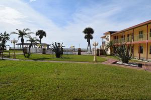 a park in front of a building with palm trees at Sails Resort Motel in St. Pete Beach