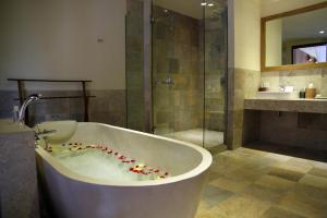 a bath tub in a bathroom with a shower at Sapodilla Ubud in Ubud