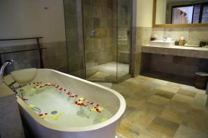 a bathroom with a tub with a shower and a sink at Sapodilla Ubud in Ubud