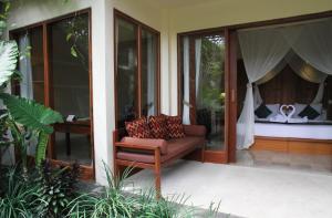 a chair sitting on a porch next to a bedroom at Sapodilla Ubud in Ubud