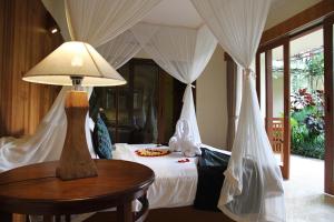 a bedroom with a bed with a table and a lamp at Sapodilla Ubud in Ubud