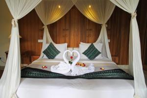 a bed with two swans dressed in white at Sapodilla Ubud in Ubud