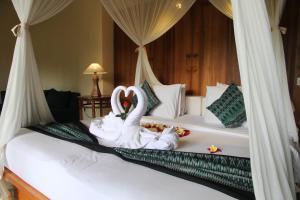 two swans sitting on a bed in a room at Sapodilla Ubud in Ubud