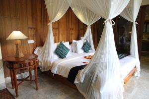 a bedroom with a bed with mosquito nets at Sapodilla Ubud in Ubud
