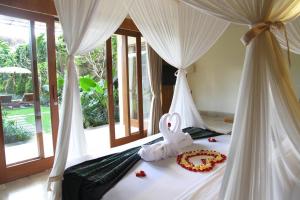 a bedroom with two beds with white drapes at Sapodilla Ubud in Ubud