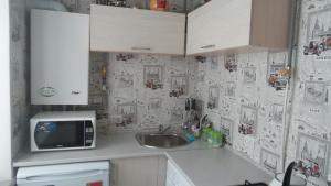 eine Küche mit einer Spüle und einer Mikrowelle in der Unterkunft вулиця 29-го Вересня 2\25 in Krementschuk