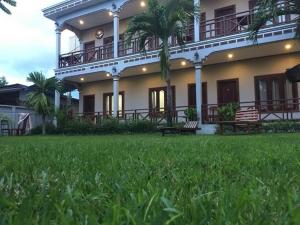 a large building with a green lawn in front of it at Mama Leurth Sunset Guesthouse in Don Det