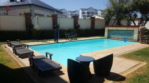 a swimming pool with two chairs and a table at Strelitzia Apartment in Edenvale