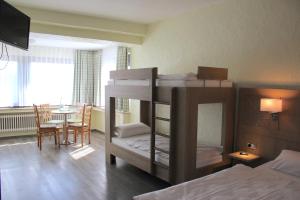 Landhotel Eifelblick في ستادتكيل: غرفة نوم مع سرير بطابقين وغرفة طعام مع طاولة