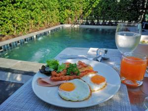 a plate of breakfast food on a table next to a swimming pool at T Villas Hua Hin in Khao Tao