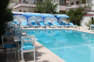 a pool with chairs and umbrellas next to a hotel at Altinyaz Hotel in Çeşme