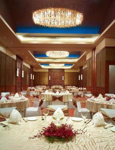 a dining room with tables and chairs and a chandelier at Vivanta Coimbatore in Coimbatore