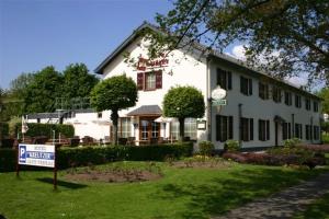 een groot wit gebouw met een bord ervoor bij Hotel Kreutzer in Heijenrath