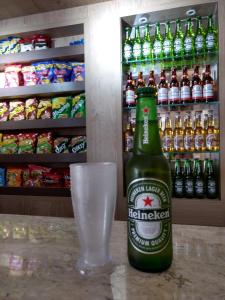 a bottle of beer and a glass in front of a refrigerator at Hotel Palacio in Paranaguá