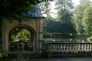 a building with a table and chairs next to a lake at Jagdschloss-Bellin in Bellin
