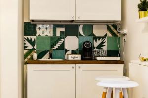 a kitchen with white cabinets and green and white tiles at La casa di Alice in Salerno