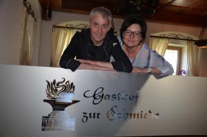 mężczyzna i kobieta stojący za znakiem w obiekcie Gasthof zur Schmiede w mieście Berg im Drautal