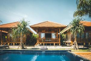 a resort with a swimming pool in front of a house at Ocho Bali Surf Camp in Uluwatu