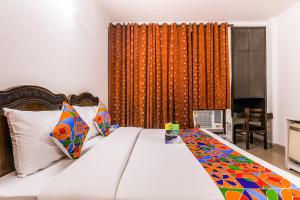 una camera da letto con un grande letto bianco con cuscini colorati di FabExpress Hemkunt Mansion a Noida