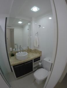 a bathroom with a toilet and a sink and a mirror at Apartamento Cobertura Duplex in Bombinhas +13 photos