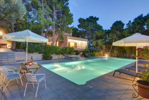 a swimming pool with tables and chairs and umbrellas at Villa Loutraki Sunset in Loutraki