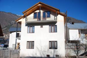 Casa blanca con techo de madera en New Seti Guest House, en Mestia
