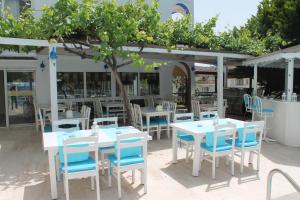 a restaurant with white tables and blue chairs at Altinyaz Hotel in Çeşme