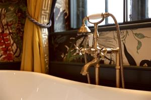 a bath tub with a faucet next to a window at The Bedford Balham - Live Music Venue in London