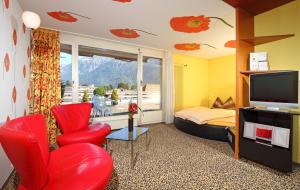 a living room with a red chair and a television at Stella Swiss Quality Hotel in Interlaken