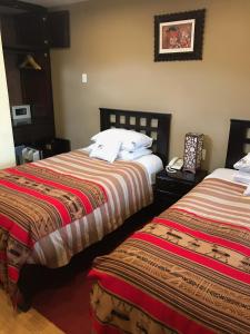 a hotel room with two beds and a phone at Cusco Bed and Breakfast in Cusco