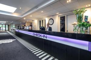 a man standing at a check in counter in a lobby at Van Der Valk Hotel Rotterdam Nieuwerkerk in Nieuwerkerk aan den IJssel