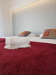 1 cama con sábanas blancas y manta roja en Maria Violeta Tourism Apartment, en Cadaval