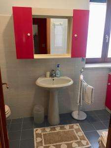 ein Badezimmer mit einem Waschbecken und roten Schränken in der Unterkunft La casa di Marty B&B in Berceto