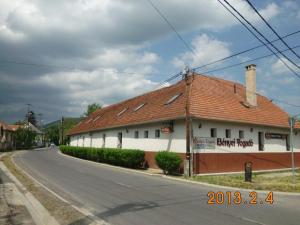 a white building with a red roof on a street at Bényei Fogadó Panzió és Étterem in Erdőbénye