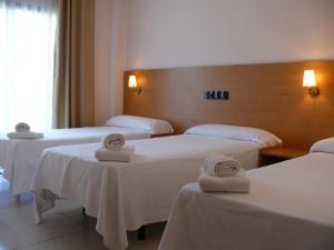 a hotel room with three beds with towels on them at Bay Hotel in Roses