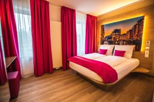 Schlafzimmer mit einem großen Bett und roten Vorhängen in der Unterkunft Hotel Luckys Inn in Hamburg