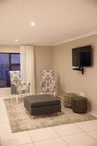 a living room with a couch and two chairs and a flat screen tv at Eden Guesthouse B&B in Dana Bay