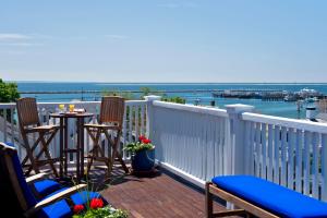 un balcón con 2 sillas y una mesa con vistas al agua en Benchmark Inn en Provincetown