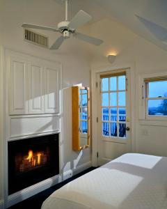 a white bedroom with a fireplace and a bed at Benchmark Inn in Provincetown