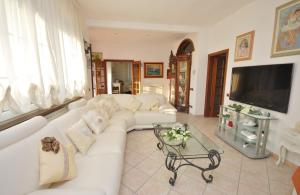 a living room with a white couch and a tv at Raffinato attico vicino al mare con solarium Lido di Camaiore in Camaiore