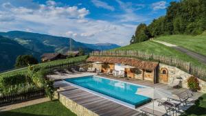 a villa with a swimming pool on top of a hill at Apartments Pitschlmann in Völs am Schlern