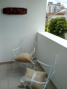 einen Stuhl auf einem Balkon mit einem Fenster in der Unterkunft DTO SERRANO in Tandil