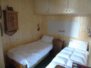 a bedroom with two beds and a wooden wall at Hs4U Chalet sulle piste - Dolomiti - Madonna di Campiglio in Madonna di Campiglio