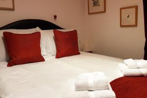 a bedroom with a bed with red and white pillows at Dove Cottage, Tideswell in Tideswell