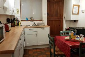 cocina con armarios blancos y mesa con mantel rojo en Dove Cottage, Tideswell, en Tideswell