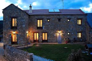 una gran casa de piedra con sus luces encendidas en Casa Rural Estarrún, en Aísa