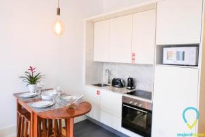 a kitchen with white cabinets and a wooden table at Simply Porto in Porto