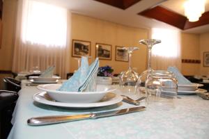 une table avec des assiettes, des verres et des serviettes dans l'établissement Hotel Da Remo, à Roccaraso