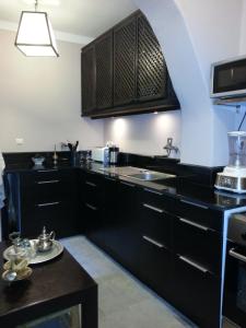 eine Küche mit schwarzen Schränken und einem Waschbecken in der Unterkunft Riad Azza in Marrakesch